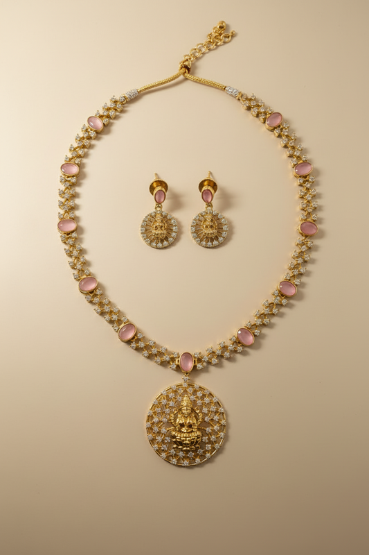 Gold necklace and earrings with pink stones on a white background