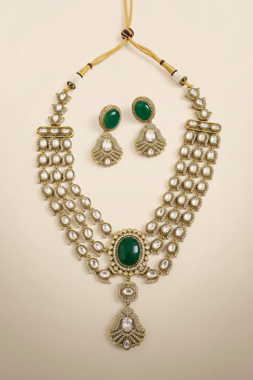 Gold necklace with green stones and matching earrings on a textured white surface