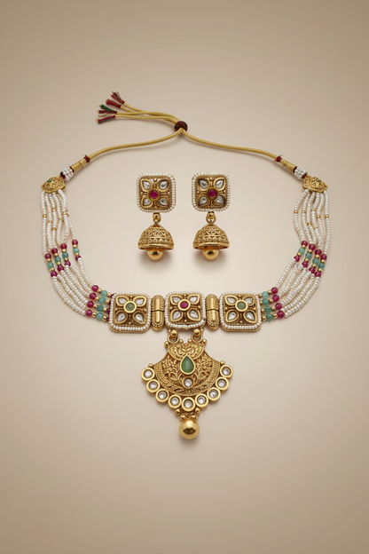 Gold jewelry set with necklace and earrings on a textured white surface