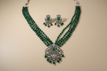 Green beaded necklace with silver and green accessories on a beige background