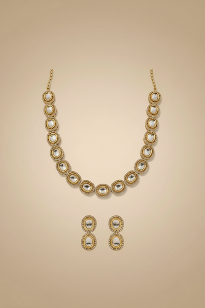 Gold necklace and earrings set on a beige background