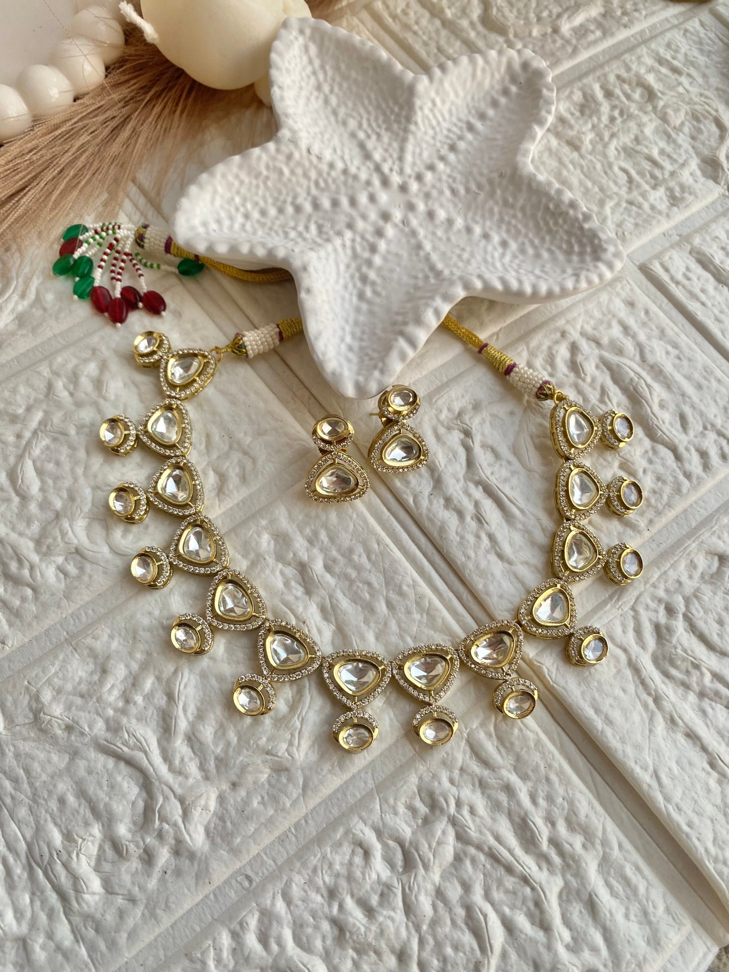 Gold necklace and earrings on a textured white surface
