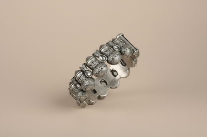 Silver bracelet with intricate designs on a beige background